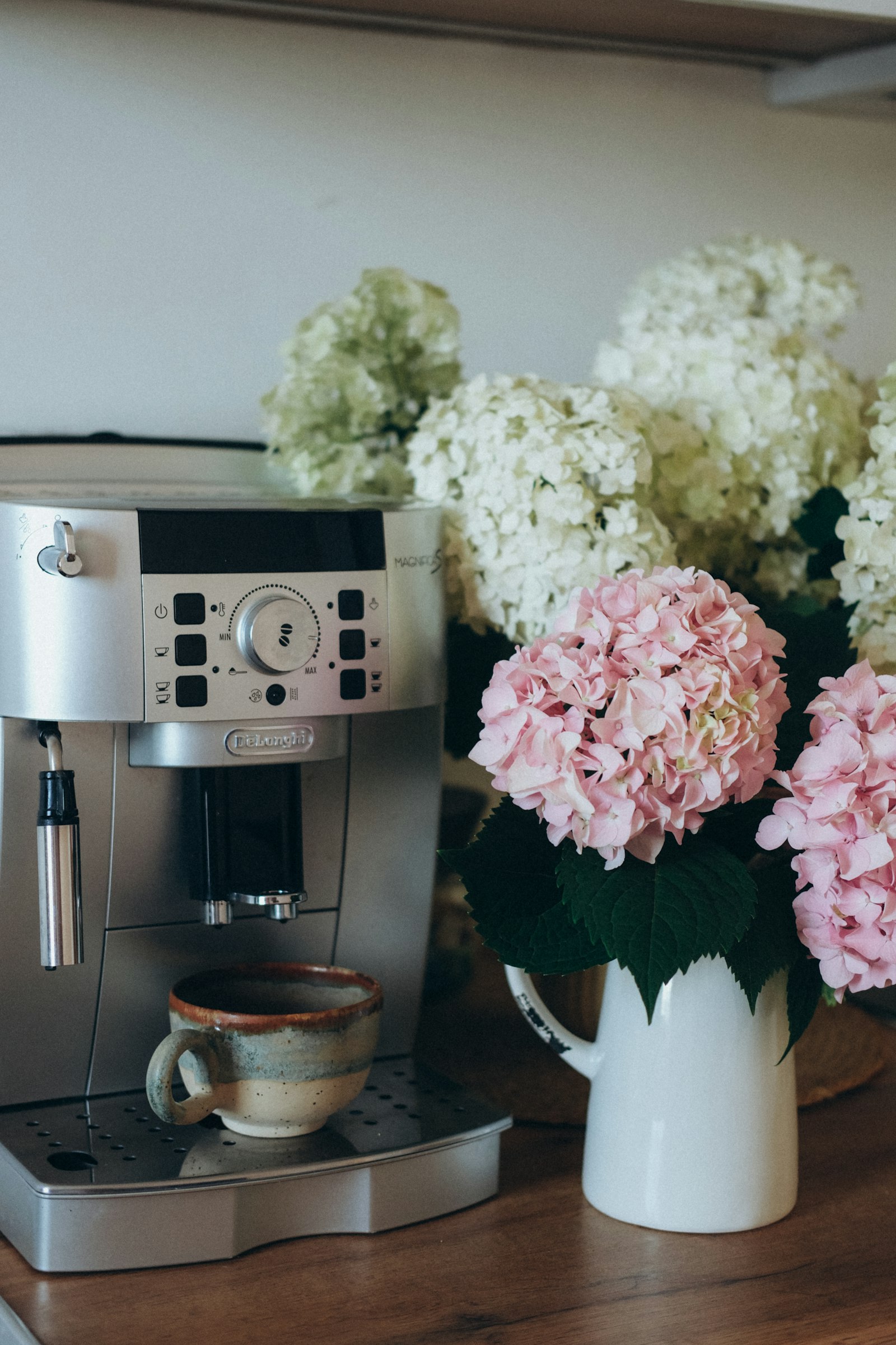 De’Longhi volautomaat op het aanrecht naast een vaas hortensia’s